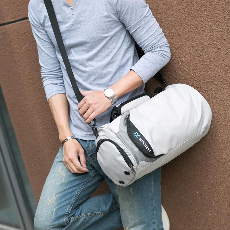 Light gray gym duffel bag carried with front zipper and X sport logo panel.
