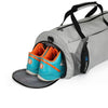 Light gray duffel bag with shoe compartment holding orange-and-teal sneakers, black zipper.