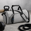 Gym & travel duffel bag in light gray with black handles, straps, and zipper pockets.